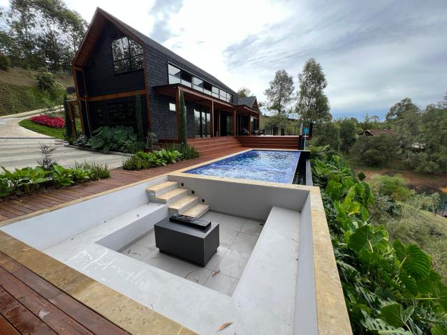 Dark chalet-style lakefront villa with a pool, wood deck and views of the Guatapé reservoir.