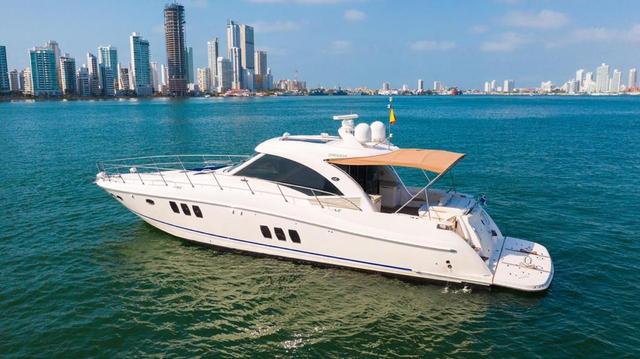 White Sea Ray Sundancer with a tan bimini top on turquoise water in front of the Cartagena skyline