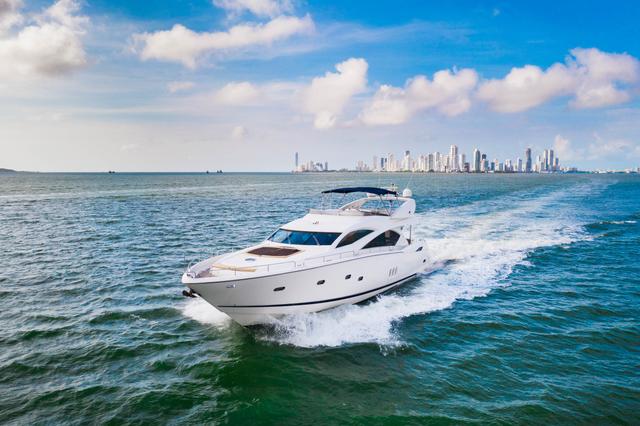 White Sunseeker flybridge yacht cruising at speed with a white wake and the Cartagena skyline on the horizon